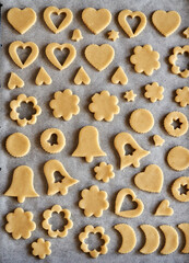 Shapes made of raw pastry dough on baking paper - preparation of Linzer Christmas cookies
