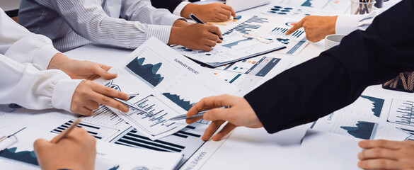A diverse team engages in a collaborative business meeting, analyzing various graphs and charts to enhance strategic planning and financial performance in a modern office setting. SACTR