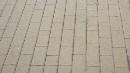 A close-up view of a weathered stone pavement featuring rectangular tiles in a sandy hue. This textured surface is suitable for backgrounds in architectural or outdoor projects.