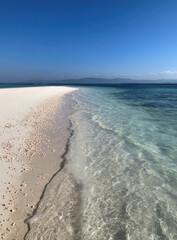 Pristine white sand beach meets turquoise ocean under a brilliant blue sky