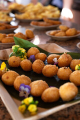 Crispy golden fried cheese balls served on a banana leaf and decorated with edible flowers, perfect for a party or appetizer table.