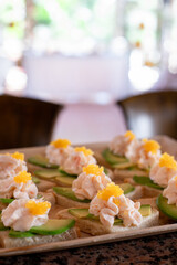 Tapas. Small gourmet sandwiches with avocado, mousse, and decorative caviar topping. Served on a stylish plate for upscale events or catering.