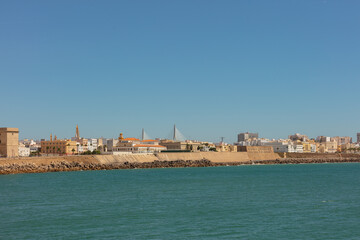 Coastal view with rocky shore and fortress in the distance. Cadiz, Andalusia, Spain, September 2025.