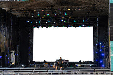Stage crew setting up concert production with massive LED screen