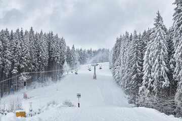 Ski slope with a chairlift through a snowy forest.