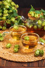 Hop Tea with Fresh Hops in Glass Cups and Teapot on Rustic Background