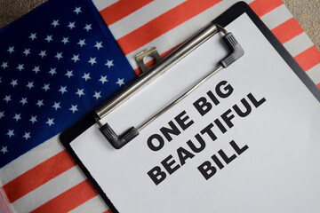 Concept of one big beautiful bill with the United States flag write on clipboard isolated on Wooden Table.