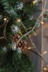 Christmas string light garland with glowing bulbs draped on a wooden pillar. Warm holiday decoration for festive interior.