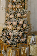 Decorated Christmas tree with glowing lights and ornaments, surround by golden and silver presents. Holiday celebration interior background for winter.