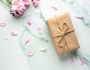 Simple wrapped gift with twine on pastel mint marble background, decorated with flower petals. 