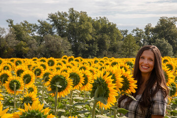 Young brunette smiling at camera in sunflower field