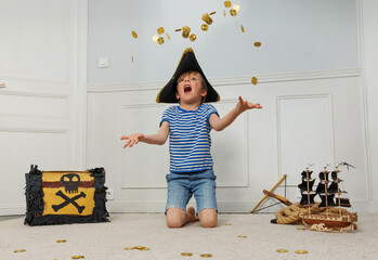 Pirate boy stands behind treasure chest tossing coins overhead