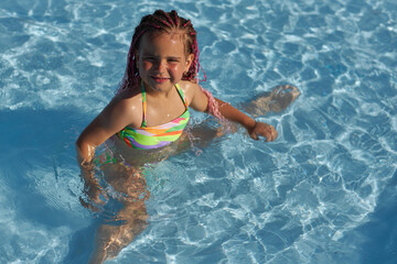 Joyful girl playing in a pool on a sunny day