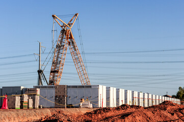 Construction site with a large crawler crane positioned beside rows of battery storage units and electrical infrastructure supporting renewable energy and grid-scale storage development projects