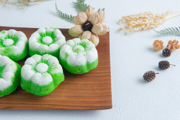 Freshly made Indonesian steamed cakes putu ayu with coconut topping placed on a wooden table, traditional homemade snack.