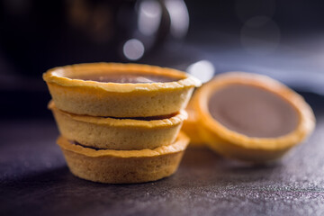 Sweet chocolate tartelettes on black table.