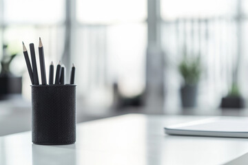 Soft daylight on desk. Black pencils in holder. Creative office setup for productivity and workspace design.