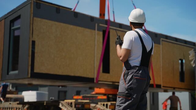 Construction worker supervising prefabricated house transportation