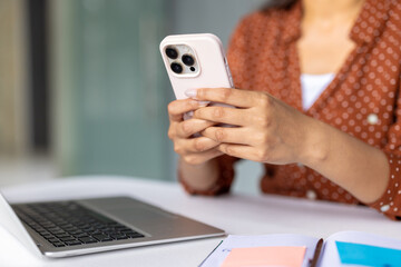 Businesswoman using smartphone and laptop in office