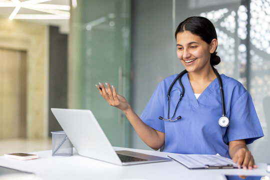 Smiling indian doctor having video conference on laptop in hospital