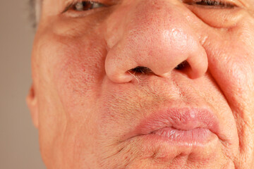 Man examine his wild nose hairs so he can pluck or trim them out