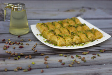 Warbat Pastries with Cream and Pistachios in plate on wooden table side view of Middle Eastern dessert