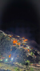 Nighttime hillside village glows with scattered lights, revealing winding paths and stone buildings nestled in mountainous terrain.  
📍Hawraman Takht, Kurdistan 