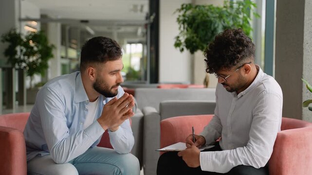 Psychologist listening to patient and taking notes during therapy session