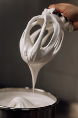 Whipped marshmallow cream pulled from mixer, close-up of airy texture and sweet dessert base