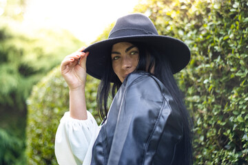 Stylish model wearing black hat and leather jacket in park