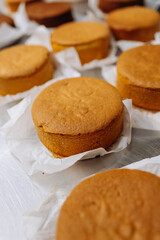 Freshly baked sponge cake layers cooling on parchment paper in a professional bakery kitchen