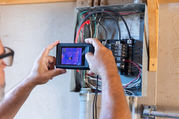 home inspector taking infrared thermography camera pictures of an electrical panel