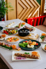 Top view of assorted grilled meats, seafood, and side dishes on a restaurant table