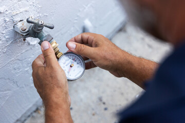 A home inspector checking water pressure with a water pressure meter