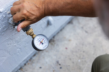 A home inspector checking water pressure with a water pressure meter
