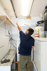 A home inspector inspecting a garage ceiling, pointing at a wire