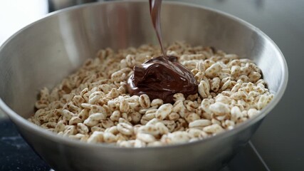 Close-up of rich melted chocolate being poured over puffed rice cereal in a bowl, preparing a delicious dessert or sweet treat for a Christmas celebration, slow motion - Powered by Adobe