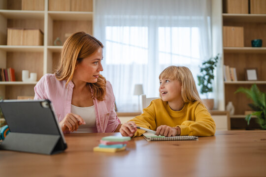 Mother helping daughter with homework, using tablet for online learning - Powered by Adobe