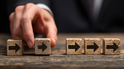 Hand is moving wooden blocks with arrows, symbolizing direction and decision making in business context. image conveys sense of progress and strategic planning