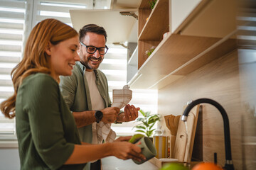 Happy couple washing dishes together in modern kitchen