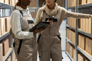 Multiethnic team of employee scan boxes bar codes in a logistics center, ensuring inventory accuracy. Shipment operations rely on stock and registration systems and efficient transportation control.