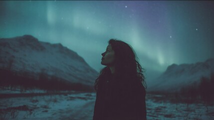 Woman silhouette gazing at northern lights over snowy mountains. Aurora borealis phenomenon in night sky. Winter landscape, nature wonder, travel concept. Starry night view.