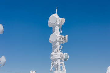 Thick rime ice covering a communications tower against a clear deep blue sky