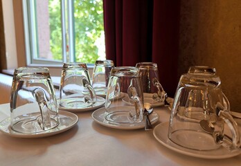 Glass cups and saucers arranged on a table in anticipation of tea time