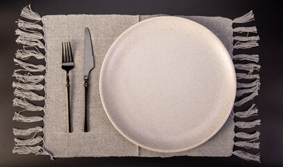 Beautiful table setting, beautiful plate, cutlery and napkin placed on a dark background, selective...