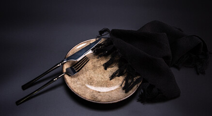 Beautiful table setting, beautiful plate, cutlery and napkin placed on a dark background, selective...