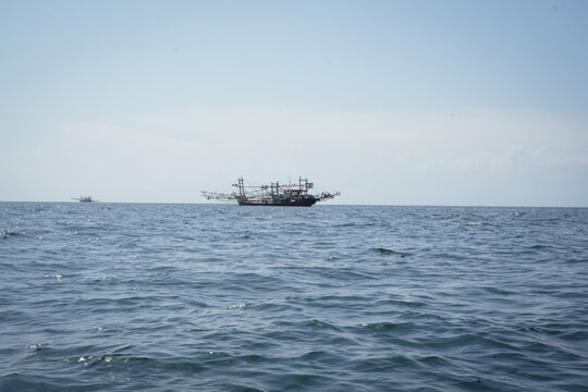 Peaceful view of fishing boats floating under a sunny sky on open ocean waters, evoking serenity