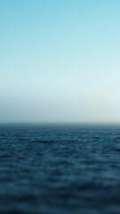 Obraz premium Misty Ocean Horizon Blue and Gray Water Under a Calm Sky vertical