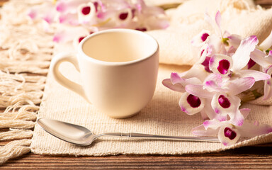 White cup, a beautiful white cup on a napkin and rustic wood surrounded by small flowers, selective focus.