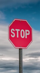 Obraz premium Red stop sign against cloudy blue sky background
